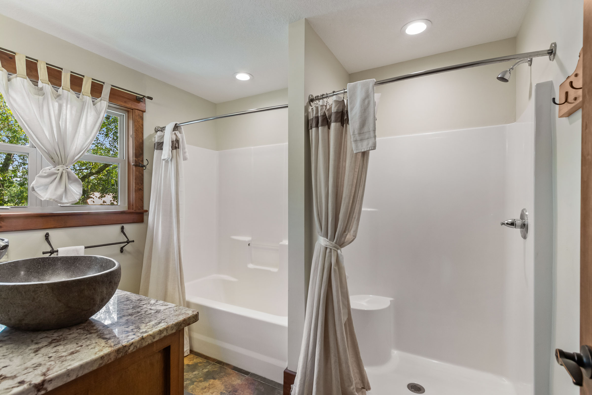 Bathroom at The Millhouse Lodge with two shower areas, soft curtains, and wood-trimmed window