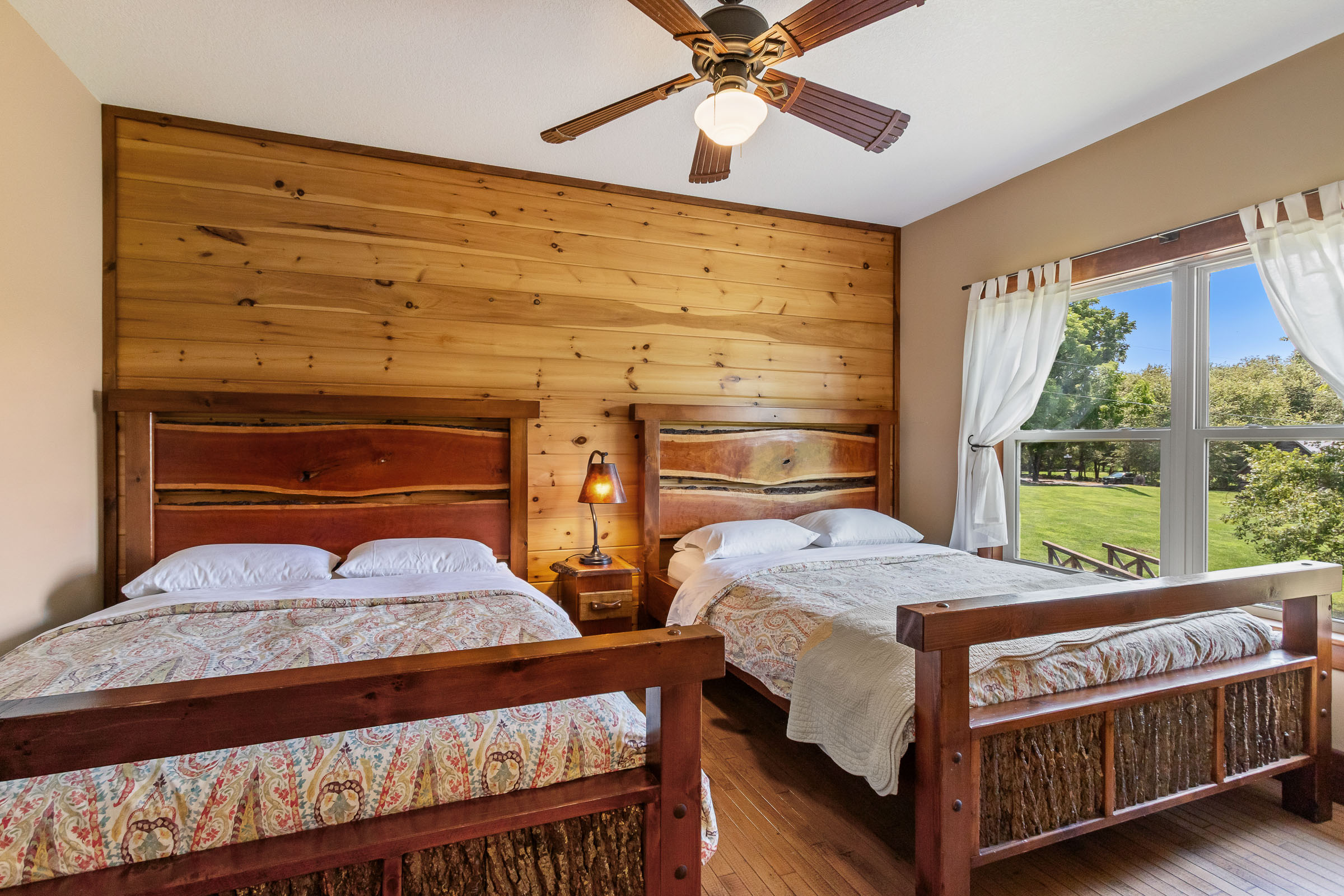 Two-bed bedroom at The Millhouse Lodge with wood headboards and farm views