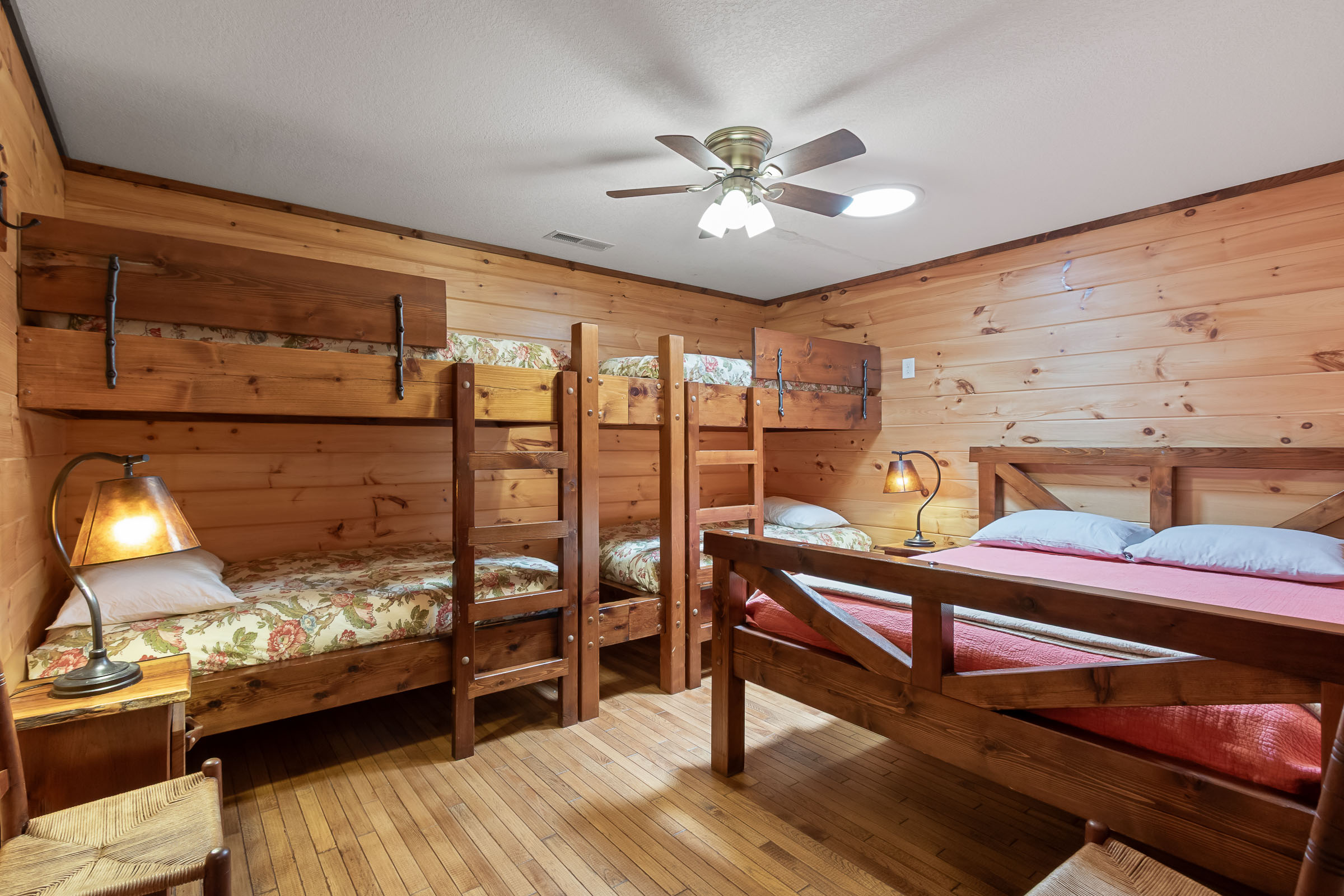 Bunk bedroom at The Millhouse Lodge with multiple wood beds and warm wood walls