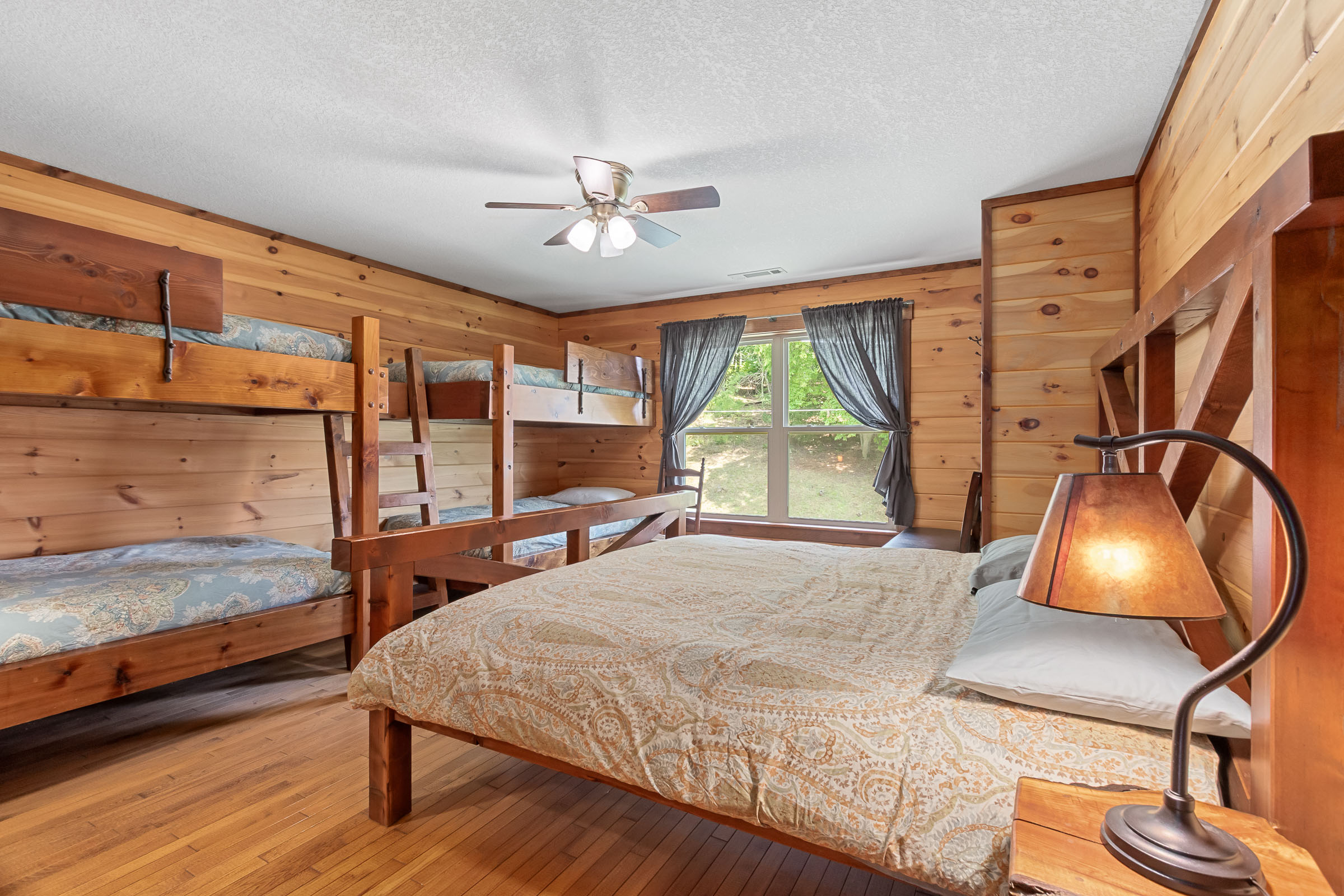 Wood-paneled bunk bedroom at The Millhouse Lodge with multiple beds and window views