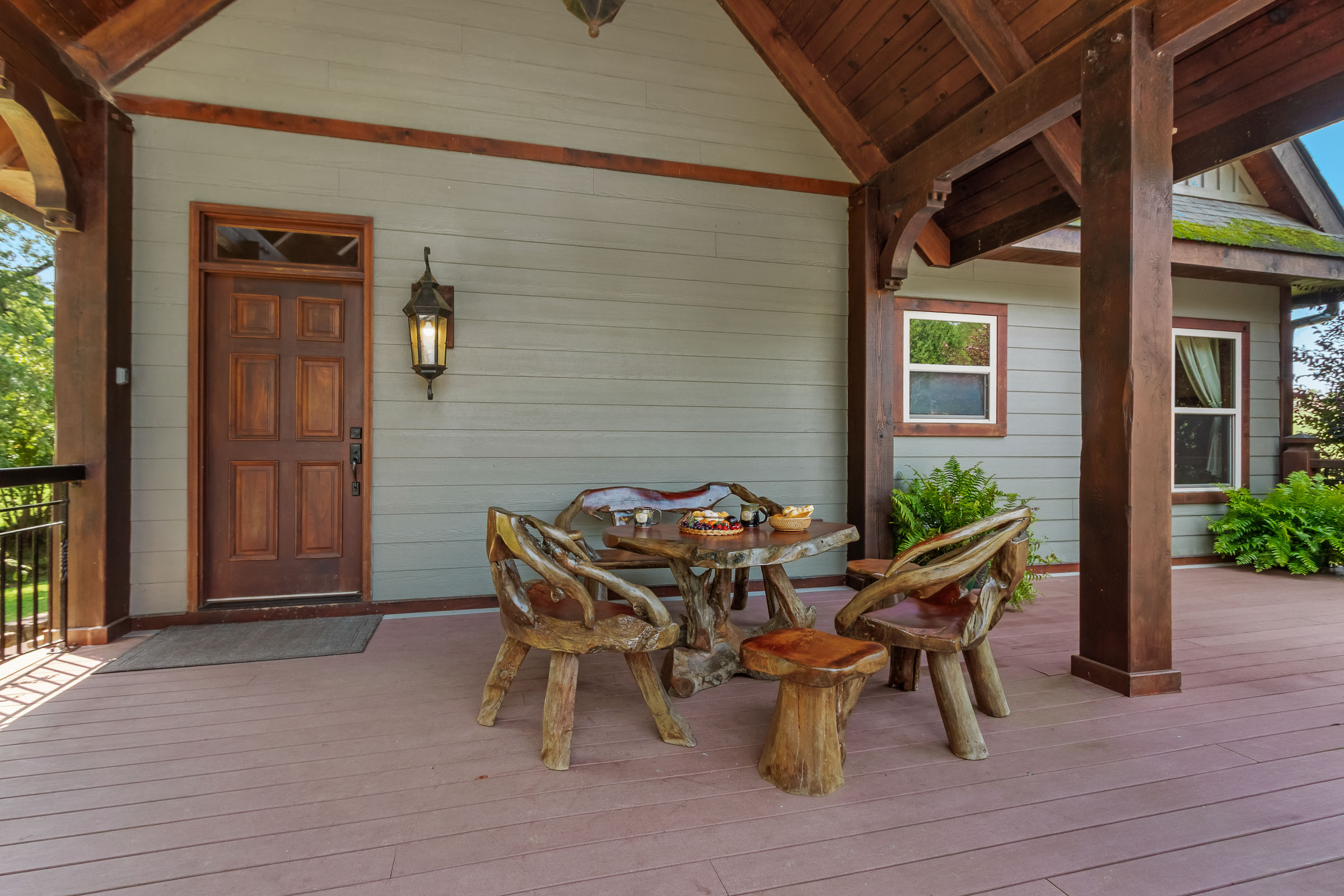 Covered porch seating at The Millhouse Lodge with rustic wood table and front door