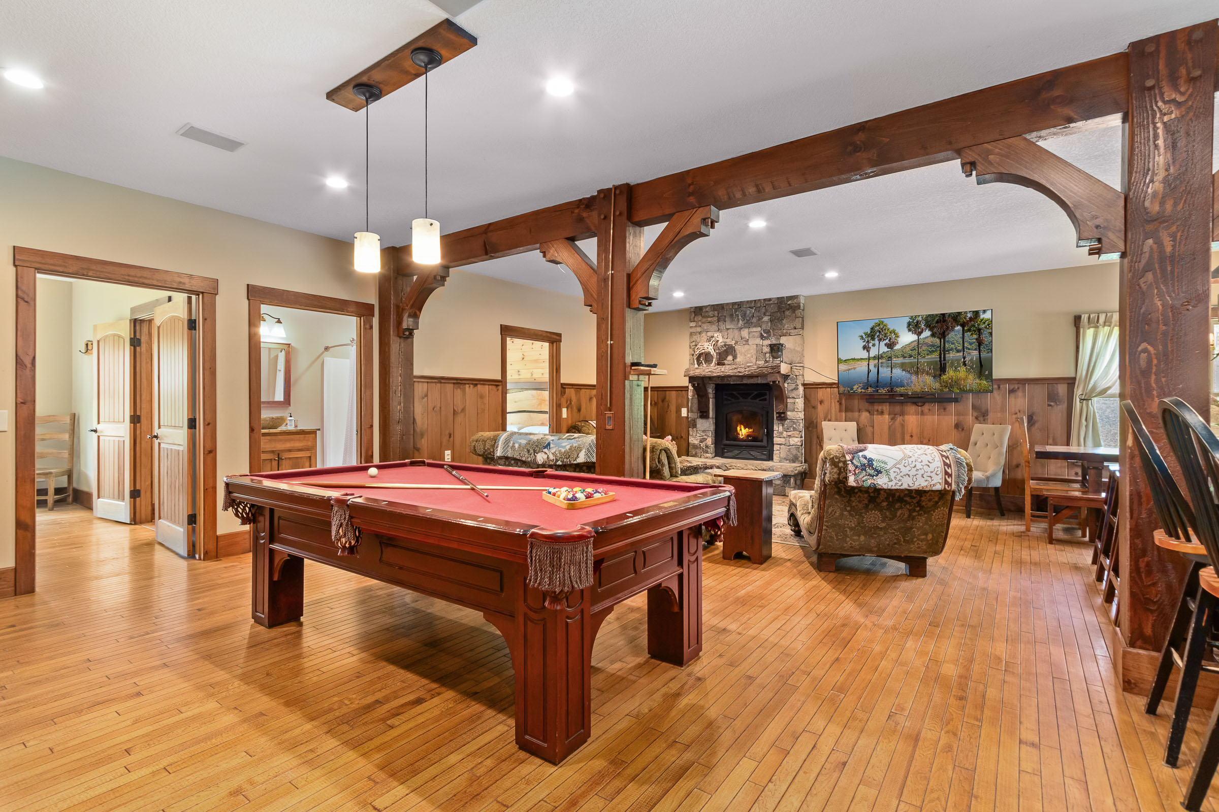 Game room at The Millhouse Lodge with pool table, timber beams, and fireplace seating