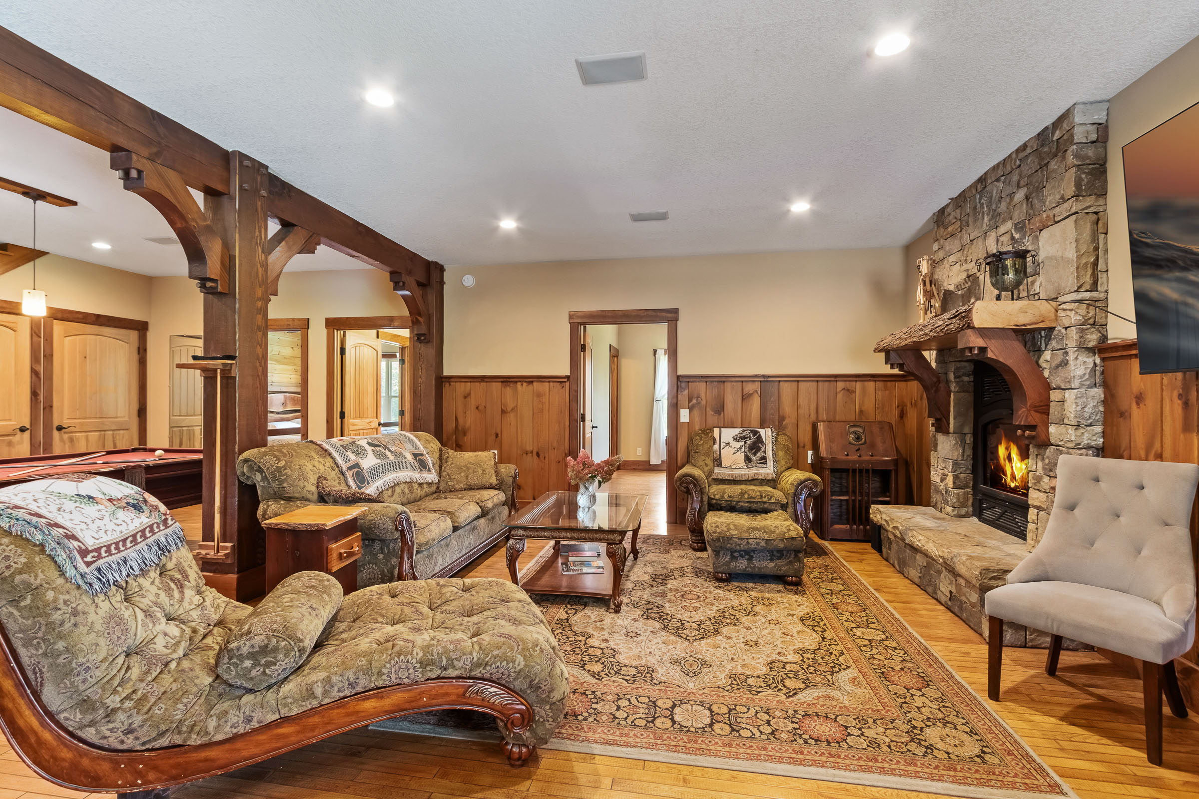 Living room at The Millhouse Lodge with sofas, timber beams, pool table, and stone fireplace
