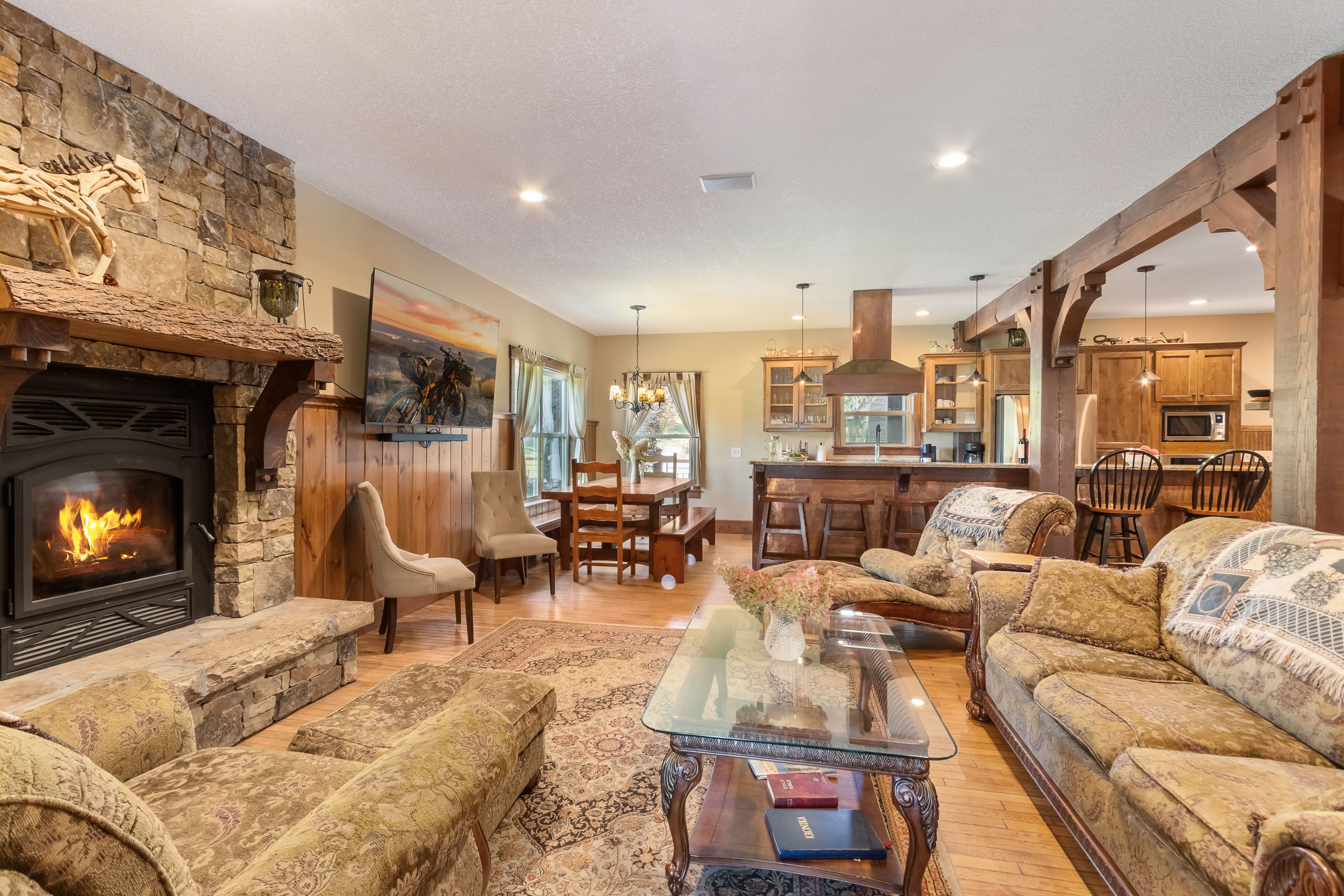 Living room, dining area, and kitchen at The Millhouse Lodge with stone fireplace