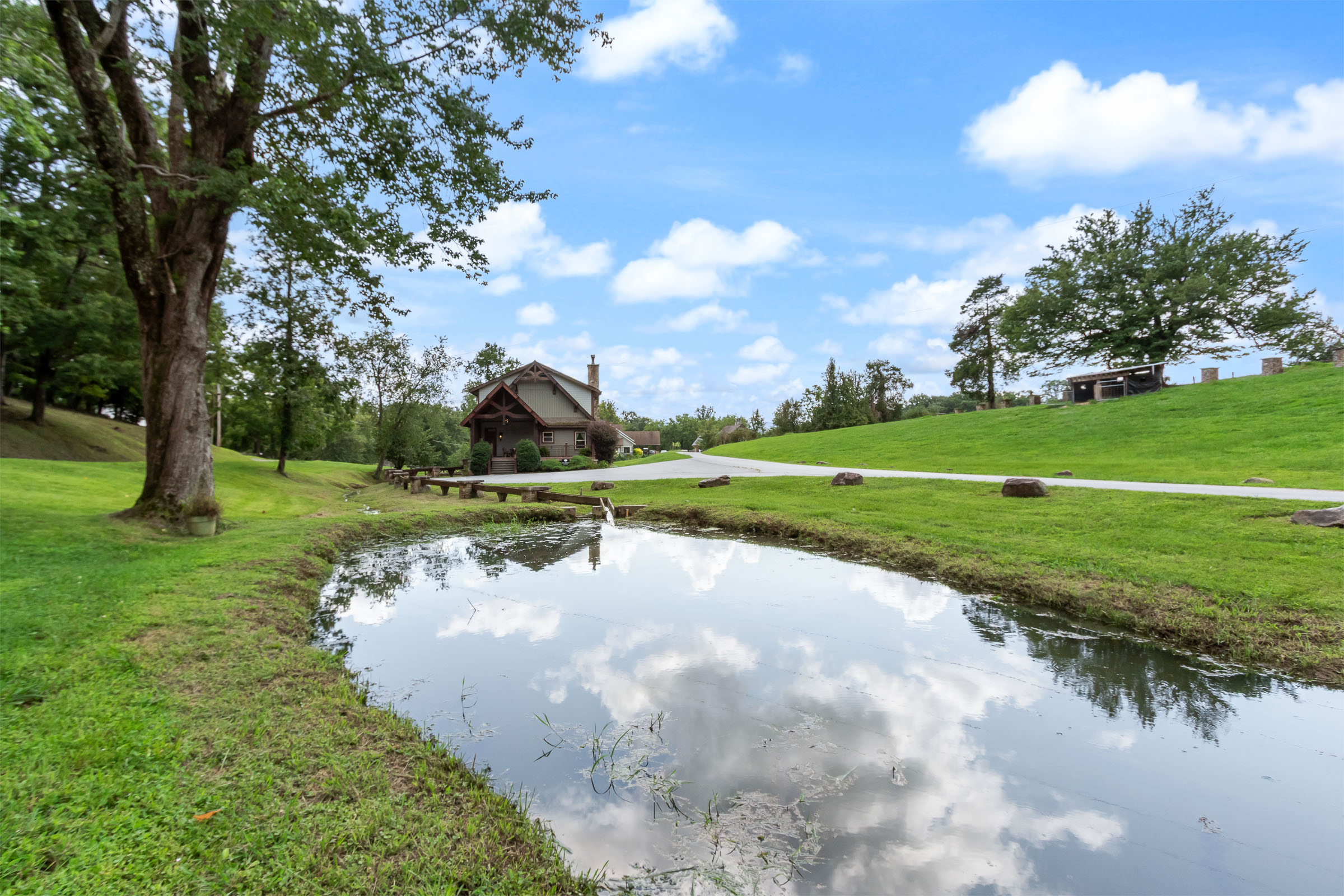 The Millhouse Lodge seen across a pond with open green lawns and blue sky