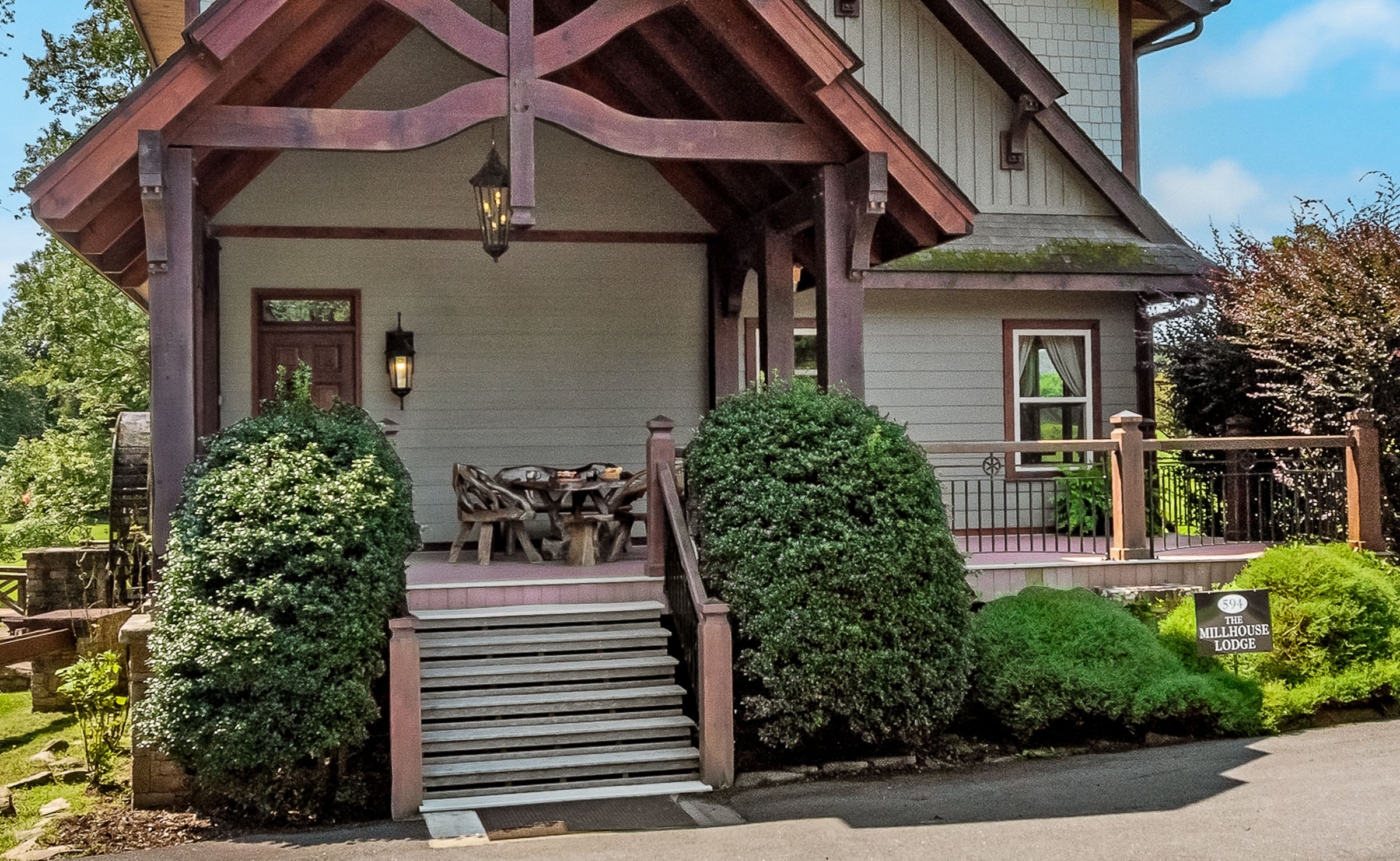 Front porch and lodge entry at The Millhouse Lodge with timber beams and green landscaping